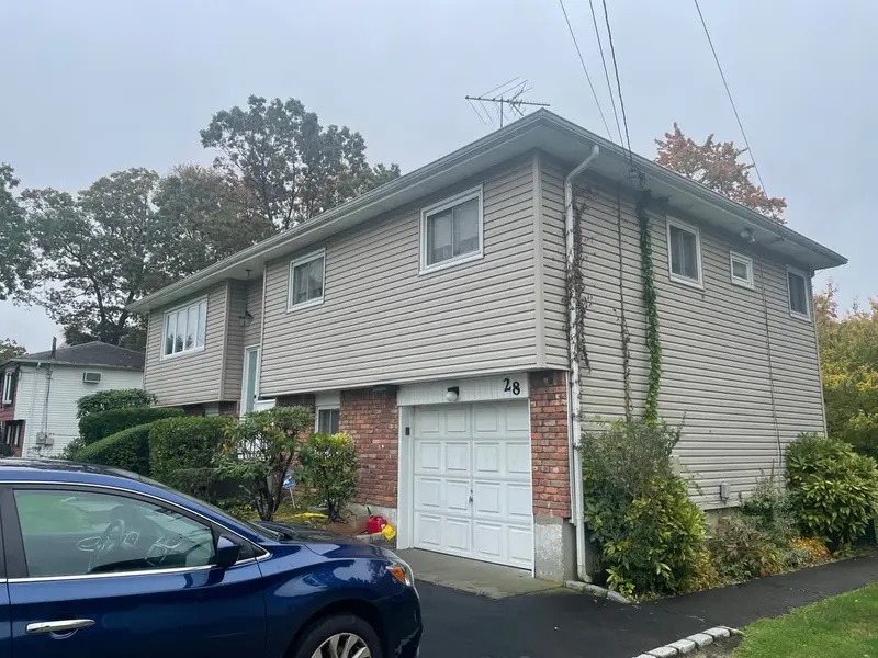 Hi-ranch with a brick-trimmed garage and tan siding, Babylon, NY